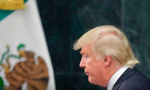 Trump com uma bandeira ao fundo