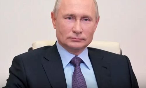 Vladmir Putin sentado com seu terno impecável